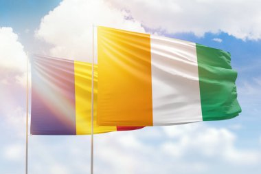 Sunny blue sky and flags of ivory coast and romania
