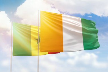 Sunny blue sky and flags of ivory coast and senegal