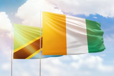 Sunny blue sky and flags of ivory coast and tanzania