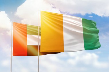 Sunny blue sky and flags of ivory coast and uae