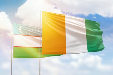 Sunny blue sky and flags of ivory coast and uzbekistan
