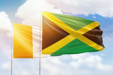 Sunny blue sky and flags of jamaica and ivory coast