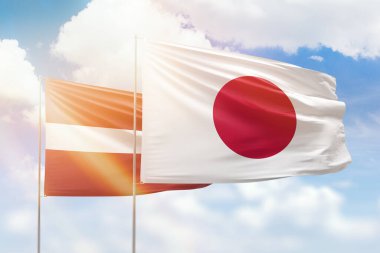 Sunny blue sky and flags of japan and latvia