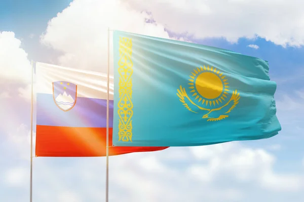 Sunny blue sky and flags of kazakhstan and slovenia