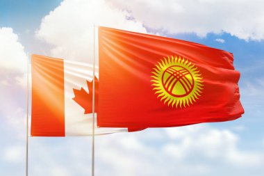Sunny blue sky and flags of kyrgyzstan and canada
