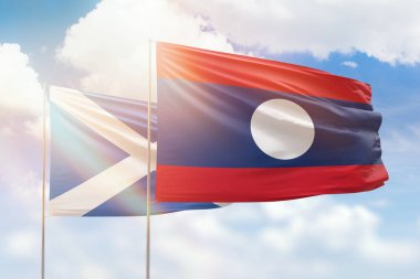 Sunny blue sky and flags of laos and scotland