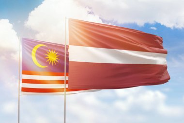 Sunny blue sky and flags of latvia and malaysia