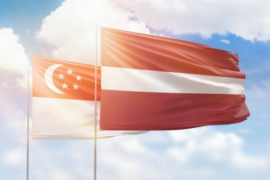 Sunny blue sky and flags of latvia and singapore