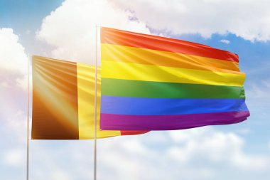 Sunny blue sky and flags of lgbt and belgium