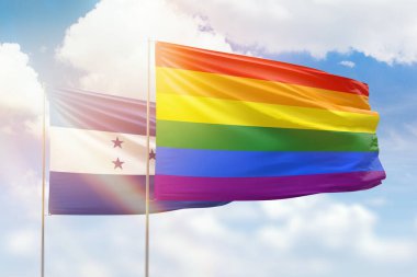 Sunny blue sky and flags of lgbt and honduras
