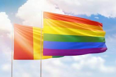 Sunny blue sky and flags of lgbt and guinea