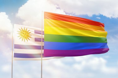 Sunny blue sky and flags of lgbt and uruguay