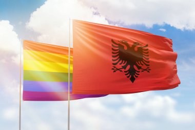 Sunny blue sky and flags of lgbt and albania