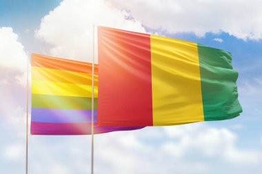 Sunny blue sky and flags of lgbt and guinea