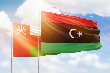 Sunny blue sky and flags of libya and oman