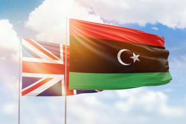 Sunny blue sky and flags of libya and united kingdom