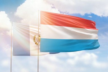 Sunny blue sky and flags of luxembourg and guatemala