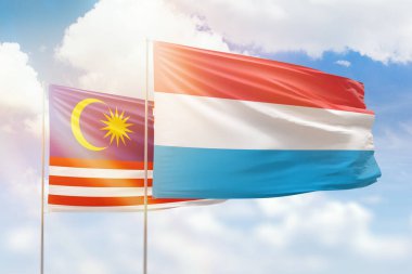 Sunny blue sky and flags of luxembourg and malaysia