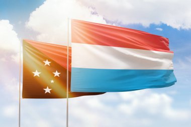 Sunny blue sky and flags of luxembourg and papua new guinea