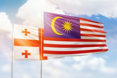 Sunny blue sky and flags of malaysia and georgia