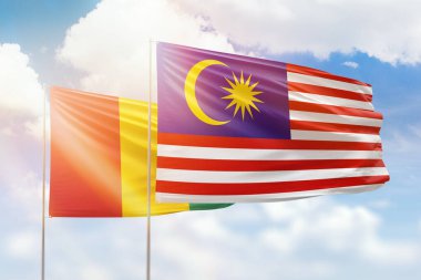 Sunny blue sky and flags of malaysia and guinea