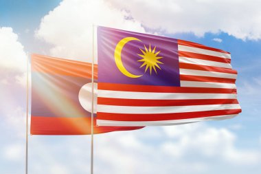 Sunny blue sky and flags of malaysia and laos