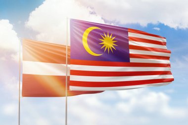 Sunny blue sky and flags of malaysia and latvia