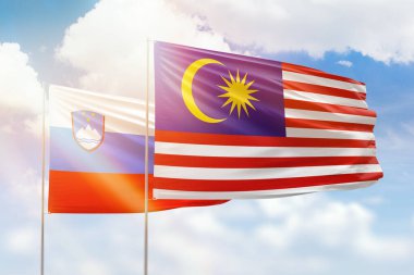 Sunny blue sky and flags of malaysia and slovenia