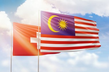 Sunny blue sky and flags of malaysia and switzerland
