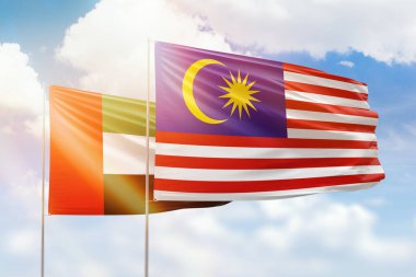 Sunny blue sky and flags of malaysia and uae