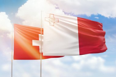 Sunny blue sky and flags of malta and switzerland