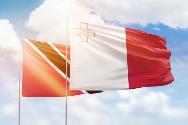 Sunny blue sky and flags of malta and trinidad and tobago