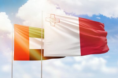 Sunny blue sky and flags of malta and uae