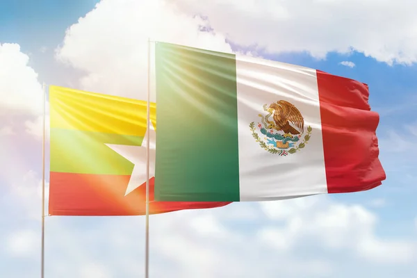 Sunny blue sky and flags of mexico and myanmar