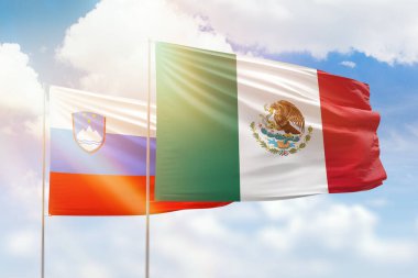 Sunny blue sky and flags of mexico and slovenia