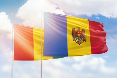 Sunny blue sky and flags of moldova and guinea