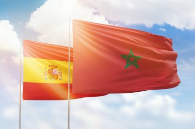 Sunny blue sky and flags of morocco and spain