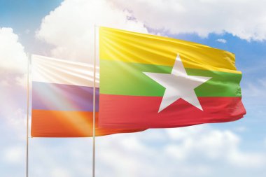 Sunny blue sky and flags of myanmar and russia