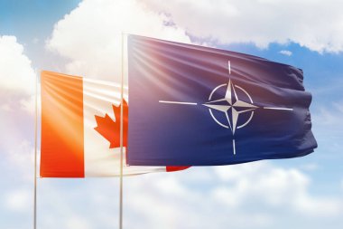 Sunny blue sky and flags of nato and canada
