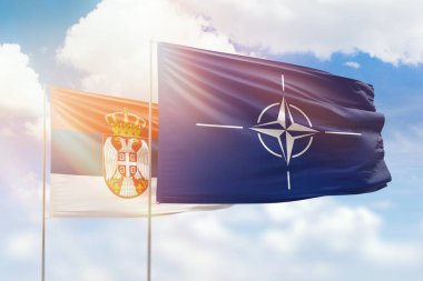 Sunny blue sky and flags of nato and serbia