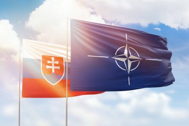 Sunny blue sky and flags of nato and slovakia