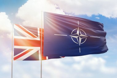 Sunny blue sky and flags of nato and united kingdom