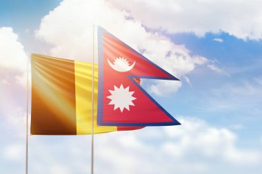 Sunny blue sky and flags of nepal and belgium