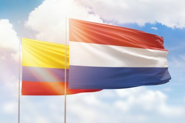 Sunny blue sky and flags of netherlands and colombia