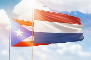 Sunny blue sky and flags of netherlands and puerto rico