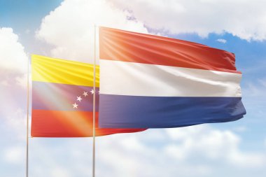 Sunny blue sky and flags of netherlands and venezuela