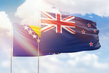 Sunny blue sky and flags of new zealand and bosnia