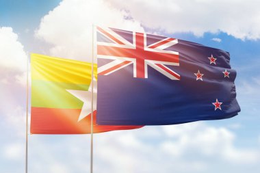 Sunny blue sky and flags of new zealand and myanmar