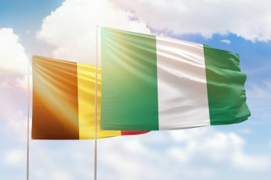 Sunny blue sky and flags of nigeria and belgium