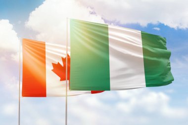 Sunny blue sky and flags of nigeria and canada